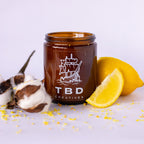 Brown jar with 'TBD Creatives' logo on a white background with lemons and cotton.