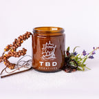 Brown mug with 'TBD Creatives' logo on a white background