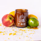 Jar with 'TBD Creatives' branding surrounded by fruits on a white background