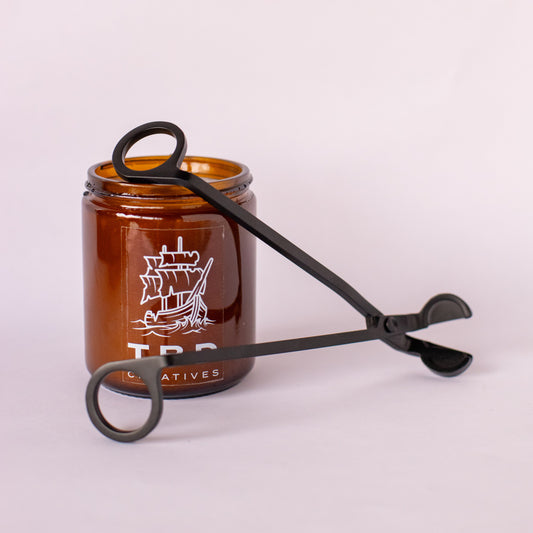 Brown glass jar with black tongs on a white background